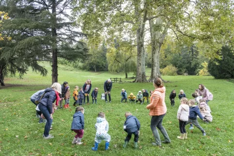 Un groupe d'enfants et d'enseignants formant un grand cercle dans le parc de l'établissement