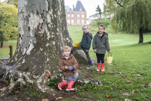 3 jeunes garçons devant un arbre dans le parc de l'établissement pendant le projet "l'école du dehors"