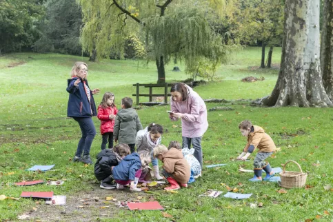 Un groupe d'enfants, une enseignante et une maman d'élève dans le parc pendant le projet "Ecole du dehors"